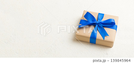 Wrapped christmas or other holiday handmade present in craft paper with colored ribbon. Present box, decoration of gift on table, top view with copy space Wrapped christmas or other holiday handmade present in craft paper with colored ribbon. Present box, decoration of gift on table, top view with copy space 139845964
