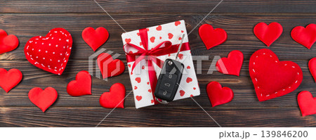 Valentine or other holiday handmade present in paper with red hearts, car keys and gifts box in holiday wrapper. box gift on Dark wooden table top view with copy space, empty space for design Valentine or other holiday handmade present in paper with red hearts, car keys and gifts box in holiday wrapper. box gift on Dark wooden table top view with copy space, empty space for design 139846200