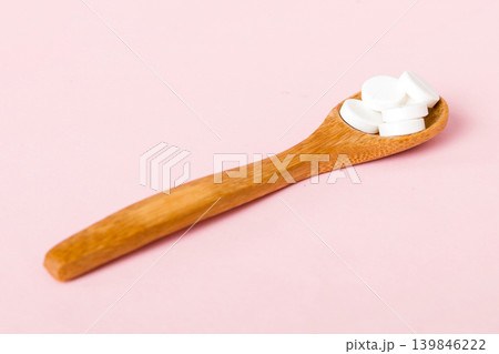 Heap of white pills on colored background. Tablets scattered on a table. Pile of red soft gelatin capsule. Vitamins and dietary supplements concept 139846222