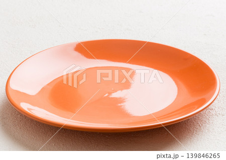Perspective view of empty orange plate on cement background. Empty space for your design Perspective view of empty orange plate on cement background. Empty space for your design 139846265