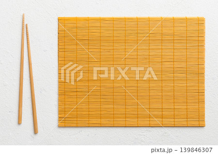 Two chopsticks and bamboo mat on cement background. Top view, copy space Two chopsticks and bamboo mat on cement background. Top view, copy space 139846307