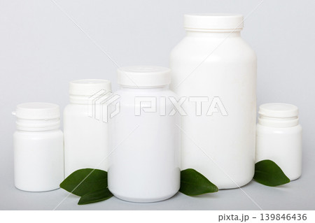 supplement pills with medicine bottle health care and medical top view. Vitamin tablets. Top view mockup bottle for pills and vitamins with green leaves, natural organic bio supplement, copy space 139846436