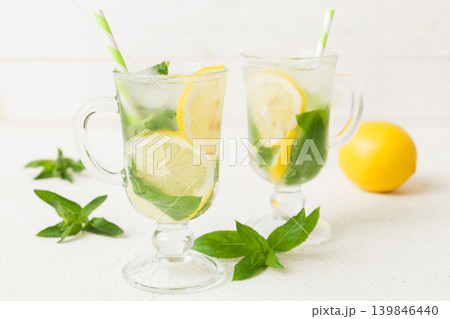 Mojito cocktail. Refreshing mojito cocktail with lime, lemon and mint in a tall glass with a stick Mojito cocktail. Refreshing mojito cocktail with lime, lemon and mint in a tall glass with a stick 139846440