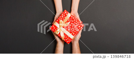 Top view of two people sharing a present on colorful background. Holiday and surprise concept. Copy space Top view of two people sharing a present on colorful background. Holiday and surprise concept. Copy space 139846718