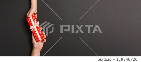 Top view of giving and receiving a gift on colorful background. Present in male and female hands. Love concept. Copy space Top view of giving and receiving a gift on colorful background. Present in male and female hands. Love concept. Copy space 139846720