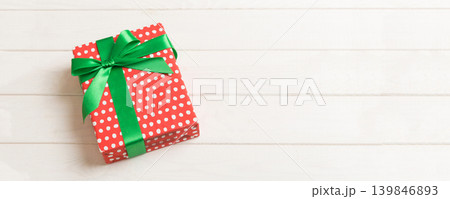 Wrapped christmas or other holiday handmade present in paper with colored ribbon. Present box, decoration of gift on table, top view with copy space 139846893