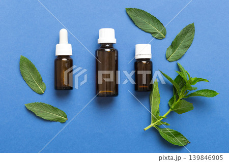 Natural Mint Essential Oil in a Glass Bottle. organic cosmetics with herbal extracts of mint on colored background Natural Mint Essential Oil in a Glass Bottle. organic cosmetics with herbal extracts of mint on colored background 139846905