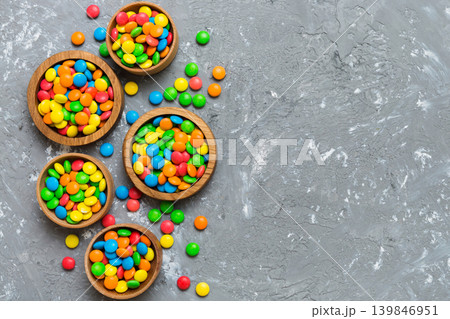 different colored round candy in bowl and jars. Top view of large variety sweets and candies with copy space different colored round candy in bowl and jars. Top view of large variety sweets and candies with copy space 139846951