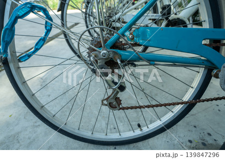 Close-up of bicycle wheel parked in bike rack at eco-friendly hotel. Sustainable transportation options for environmentally conscious guests during leisure travel. Sustainable mobility solution. Close-up of bicycle wheel parked in bike rack at eco-friendly hotel. Sustainable transportation options for environmentally conscious guests during leisure travel. Sustainable mobility solution. 139847296