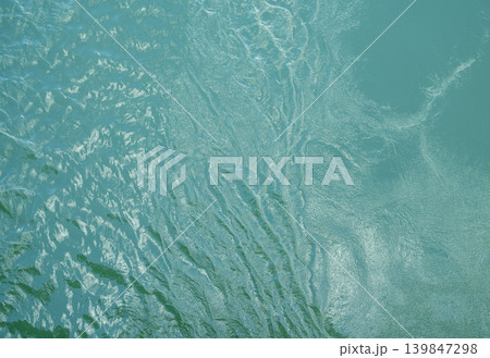 Top view of calm water surface texture with soft natural ripples. Background for eco-friendly design, peaceful concepts, and water sustainability. Aerial view blue green lake surface water background. Top view of calm water surface texture with soft natural ripples. Background for eco-friendly design, peaceful concepts, and water sustainability. Aerial view blue green lake surface water background. 139847298