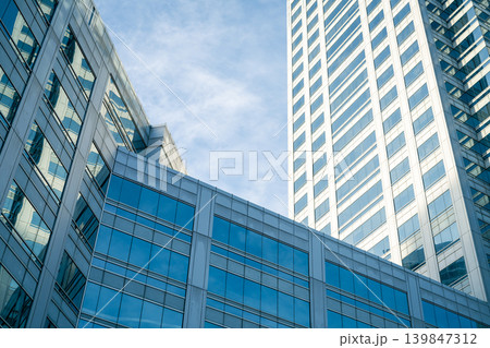 Skyscraper glass building of corporate headquarters in the downtown business area. Towering facade and windows embodying sleek, modern office environment. Financial institution. Modern architecture. Skyscraper glass building of corporate headquarters in the downtown business area. Towering facade and windows embodying sleek, modern office environment. Financial institution. Modern architecture. 139847312