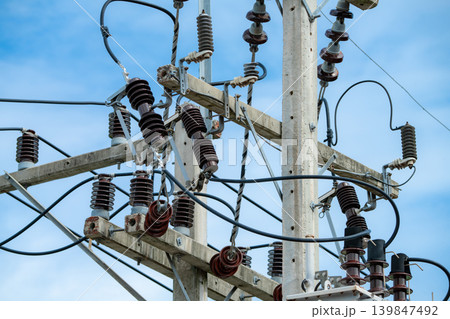 Close-up view of high voltage electrical transmission equipment on concrete utility pole with insulators and cables under blue sky showcasing modern energy infrastructure in wind farm installation 139847492