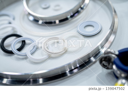 Industrial gasket and sealing rings arranged on stainless steel surface in manufacturing. Precision engineering, material quality, and components used for mechanical assembly and industrial systems. 139847502