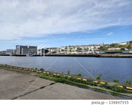 Peaceful River Scene with Plants and Buildings Under a Cloudy Sky Peaceful River Scene with Plants and Buildings Under a Cloudy Sky 139847555