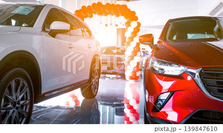 Front view of red and white SUV car. New and shiny luxury SUV car parked in modern showroom for sale. Car dealership office. Automobile retail shop. Electric car business concept. Automobile leasing. Front view of red and white SUV car. New and shiny luxury SUV car parked in modern showroom for sale. Car dealership office. Automobile retail shop. Electric car business concept. Automobile leasing. 139847610