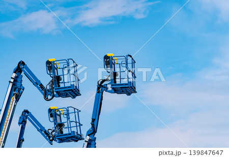 Articulated boom lift. Aerial platform lift. Telescopic boom lift against blue sky. Mobile construction crane for rent and sale. Maintenance and repair hydraulic boom lift service. Crane dealership. Articulated boom lift. Aerial platform lift. Telescopic boom lift against blue sky. Mobile construction crane for rent and sale. Maintenance and repair hydraulic boom lift service. Crane dealership. 139847647