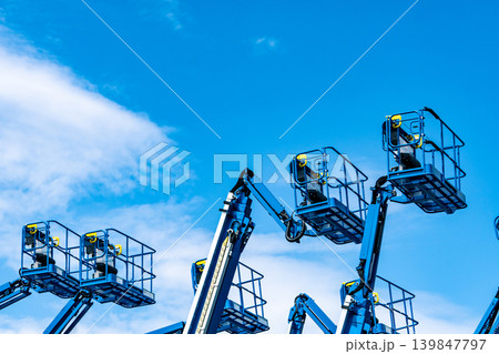 Articulated boom lift. Aerial platform lift. Telescopic boom lift against blue sky. Mobile construction crane for rent and sale. Maintenance and repair hydraulic boom lift service. Crane dealership. Articulated boom lift. Aerial platform lift. Telescopic boom lift against blue sky. Mobile construction crane for rent and sale. Maintenance and repair hydraulic boom lift service. Crane dealership. 139847797