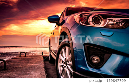 Blue luxury compact SUV at sunset, modern hybrid vehicle for beach vacation travel. Eco friendly automotive design, driving confidence. Road trip adventure and sustainable automotive technology. Blue luxury compact SUV at sunset, modern hybrid vehicle for beach vacation travel. Eco friendly automotive design, driving confidence. Road trip adventure and sustainable automotive technology. 139847799