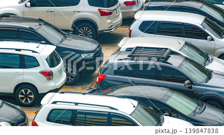 White and black car parked at concrete parking lot of shopping mall in holiday. Aerial view of outdoor car parking area of the mall. Automotive industry. Automobile parking space. Used car business. 139847838