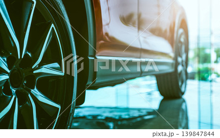 Luxury car parked in modern showroom. Auto leasing business. Car dealership concept. Closeup wheel of red shiny car show in showroom. Automotive industry. Auto glass coating and shinning business. Luxury car parked in modern showroom. Auto leasing business. Car dealership concept. Closeup wheel of red shiny car show in showroom. Automotive industry. Auto glass coating and shinning business. 139847844