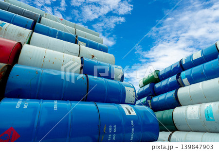 Stack of old chemical barrels. Blue, green, and red oil drum. Steel oil tank. Toxic waste warehouse. Hazard chemical barrel with red flammable liquid warning label. Hazard waste storage in a factory. 139847903