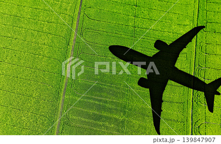 Shadow airplane flying above green field. Sustainable fuel. Biofuel in aviation. Sustainable transportation and eco-friendly flight with biofuel use. Aviation sustainability. Biofuel in air travel. 139847907