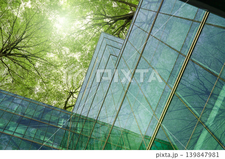 Eco-friendly building in modern city. Sustainable glass office building with trees for reducing carbon dioxide. Office building with green environment. Corporate building reduce CO2. Net zero emission Eco-friendly building in modern city. Sustainable glass office building with trees for reducing carbon dioxide. Office building with green environment. Corporate building reduce CO2. Net zero emission 139847981