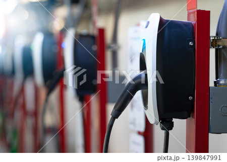 Electric car charging station for charge EV battery. Plug for electric vehicle. EV charger. Charging point at car parking lot of the mall. Clean and sustainable energy. Commercial EV charging point. 139847991