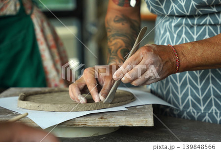 An adult man makes a ceramic plate in a workshop 139848566