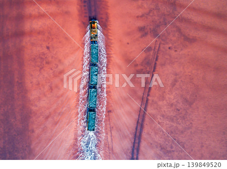 Aerial top down view of an old train rides on the railway laid in the water through the salt lake. Salt mining in Lake Burlin. Altai. Bursol. Aerial top down view of an old train rides on the railway laid in the water through the salt lake. Salt mining in Lake Burlin. Altai. Bursol. 139849520