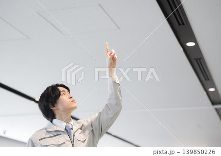 ビルの設備点検を行う若手技術者のメンテナンスイメージ 天井を指を差す ビルの設備点検を行う若手技術者のメンテナンスイメージ 天井を指を差す 139850226