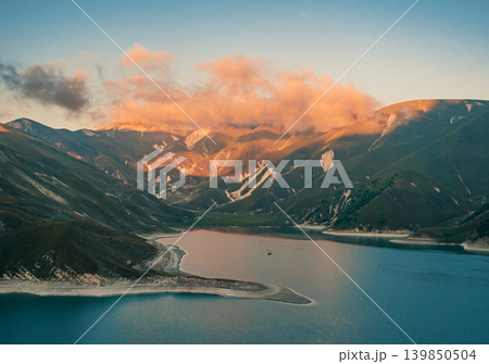 Peaceful waters of Lake Kazenoy-Am reflecting soft evening light on surrounding mountains at sunset Peaceful waters of Lake Kazenoy-Am reflecting soft evening light on surrounding mountains at sunset 139850504