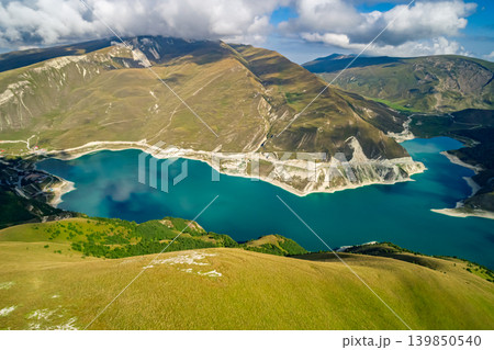 Panoramic view capturing Lake Kazenoy's striking turquoise waters contrasting with steep, sun-kissed mountains Panoramic view capturing Lake Kazenoy's striking turquoise waters contrasting with steep, sun-kissed mountains 139850540