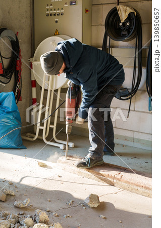 Worker using jackhammer to break concrete floor indoors Worker using jackhammer to break concrete floor indoors 139850657