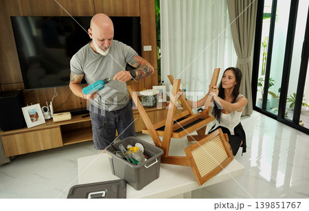 Man and woman fixing chair together to assemble living room Man and woman fixing chair together to assemble living room 139851767