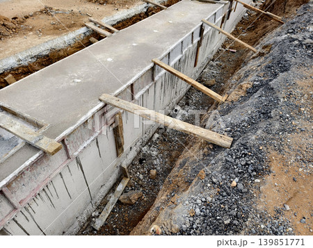 Narrow ditch with reinforcement, waterproof concrete trench bounded by soil and support stakes 139851771