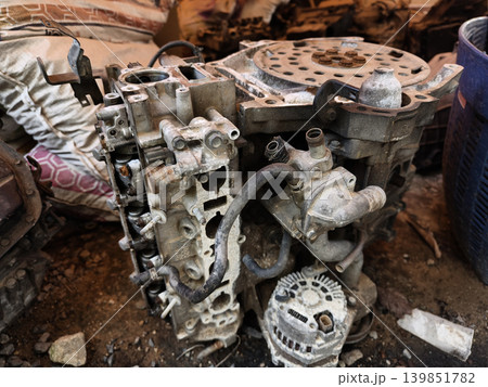 Rusted engine parts and corroded gears scattered across the sandy ground 139851782