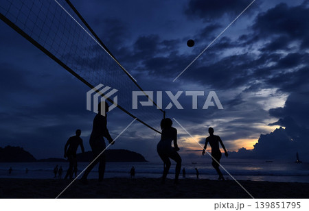Young people playing beach volleyball by the ocean at sunset Young people playing beach volleyball by the ocean at sunset 139851795