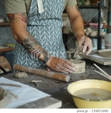 An adult man makes a ceramic plate in a workshop An adult man makes a ceramic plate in a workshop 139851860