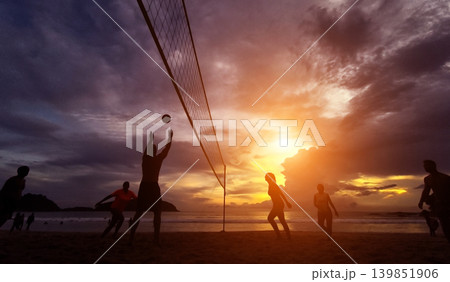 Young people playing beach volleyball by the ocean at sunset Young people playing beach volleyball by the ocean at sunset 139851906