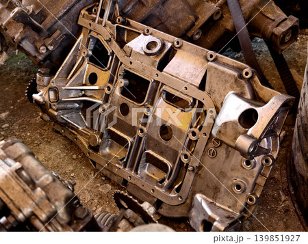 Rusted engine parts and corroded gears scattered across the sandy ground 139851927