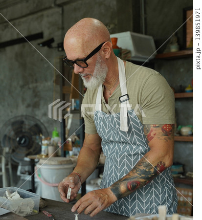 An adult man makes a ceramic plate in a workshop 139851971