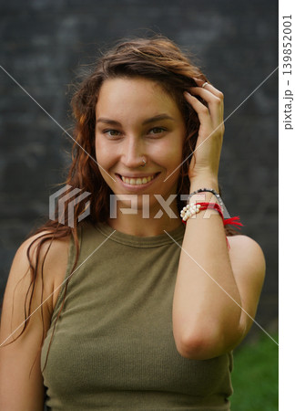 Empowered woman poses against wall with stylish attire Empowered woman poses against wall with stylish attire 139852001