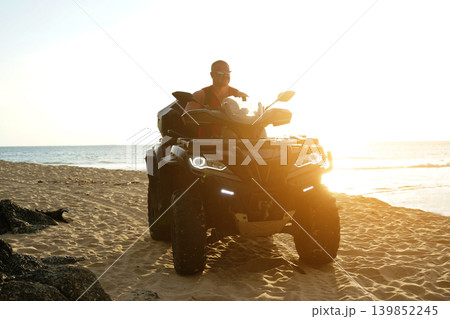 A man engages in extreme ATV riding on sand beach early in the morning 139852245