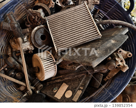 Rusted engine parts and corroded gears scattered across the sandy ground 139852354