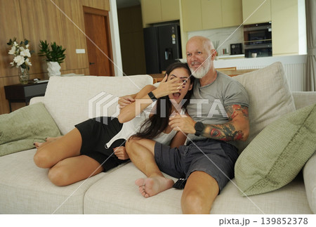 A couple expresses their love while watching TV with a modern kitchen in the background A couple expresses their love while watching TV with a modern kitchen in the background 139852378