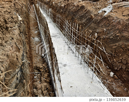 Narrow ditch with reinforcement, waterproof concrete trench bounded by soil and support stakes Narrow ditch with reinforcement, waterproof concrete trench bounded by soil and support stakes 139852639