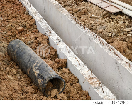 Narrow ditch with reinforcement, waterproof concrete trench bounded by soil and support stakes Narrow ditch with reinforcement, waterproof concrete trench bounded by soil and support stakes 139852900