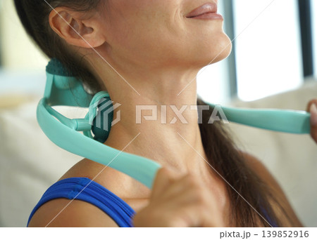 A woman uses a turquoise neck massager after a workout 139852916