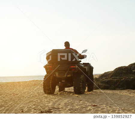 A man engages in extreme ATV riding on sand beach early in the morning 139852927
